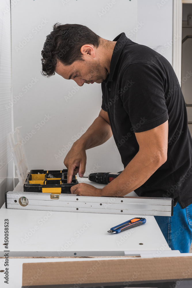 Man looking for nails in a toolbox to assemble a kitchen unit Man looking for nails in a toolbox to assemble a kitchen unit