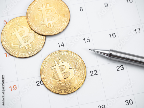 Closeup golden bitcoin and pen on calendar