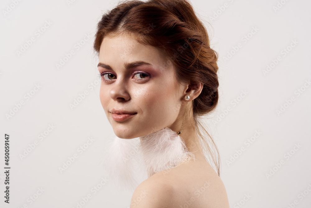 woman with bare shoulders bright makeup fluffy earrings fashion light background