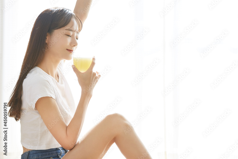 Naklejka premium 果物ジュースを飲む健康的な若い女性