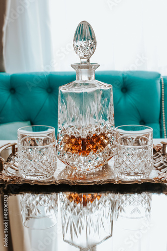 Two glasses of whiskey with ice and decanter on a wooden table