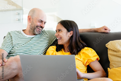 Photography Laughing father and teen daughter watching something funny in her laptop