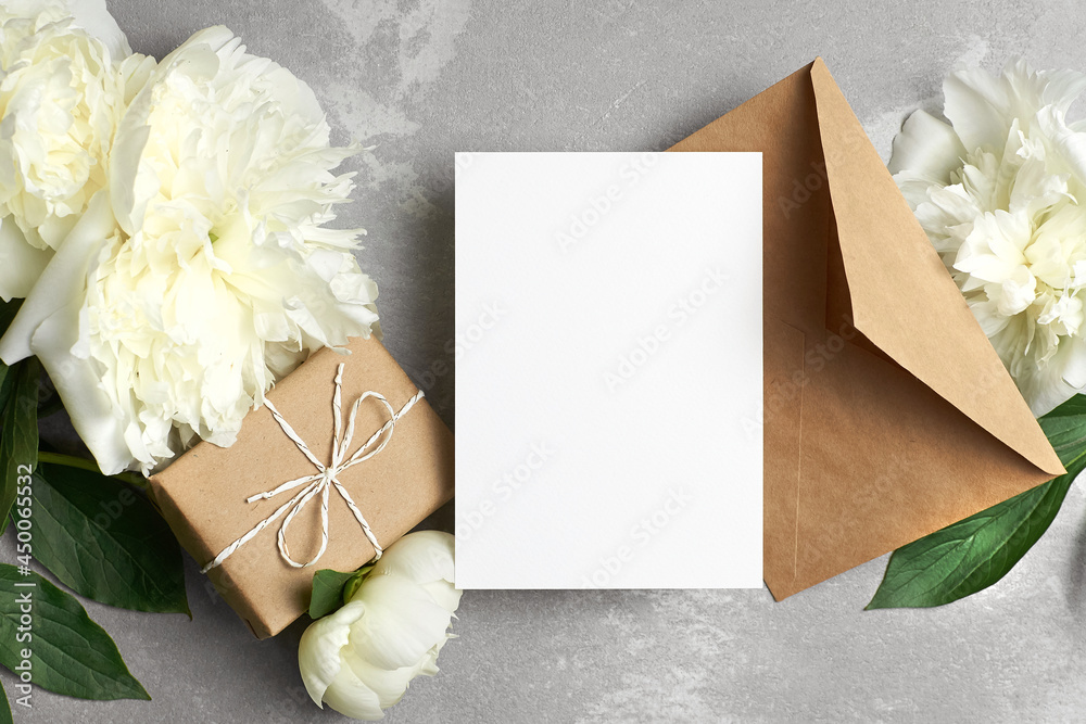 Card mockup with copy space, flat lay with white peony flowers, gift box and envelope on grey