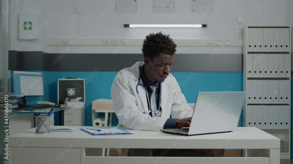 Portrait of doctor in medical cabinet sitting in uniform at desk. Close up of medic working and typing on modern laptop for professionals, healthcare private hospital office Portrait of doctor in medical cabinet sitting in uniform at desk. Close up of medic working and typing on modern laptop for professionals, healthcare private hospital office