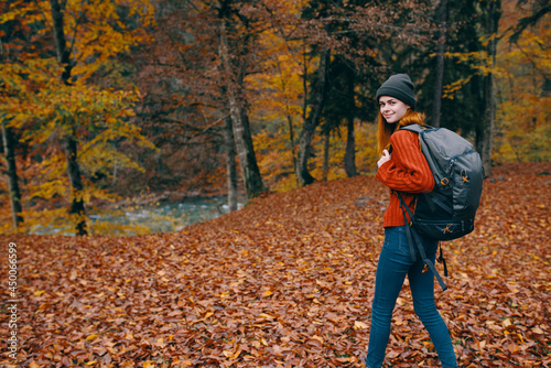 woman with a backpack walks in the autumn forest yellow leaves nature