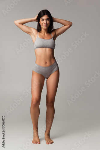 Portrait of young beautiful slim woman in lingerie posing isolated over gray studio background. Natural beauty concept.
