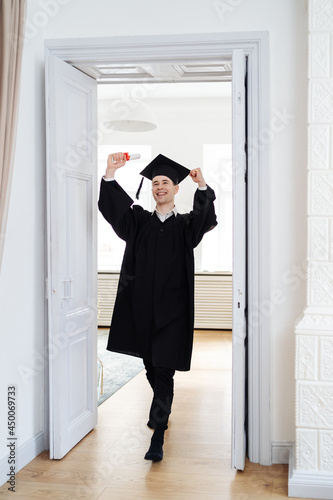 Education, graduation and people concept - happy male student with diploma at home showing his emotions