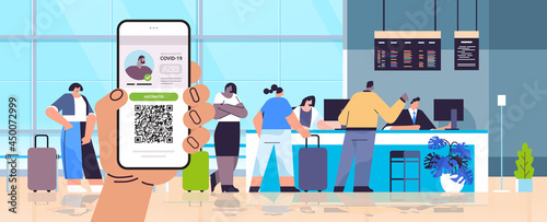 hand holding smartphone with digital immunity passport with qr code on screen risk free covid-19 pandemic