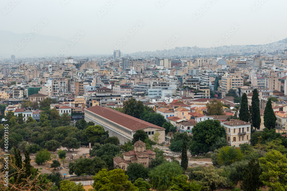 Stoa of Attalos in greenery, Church of the Holy Apostles and Athens city center with rocky hill in gray foggy day from Areopagus - Hill near Acropolis