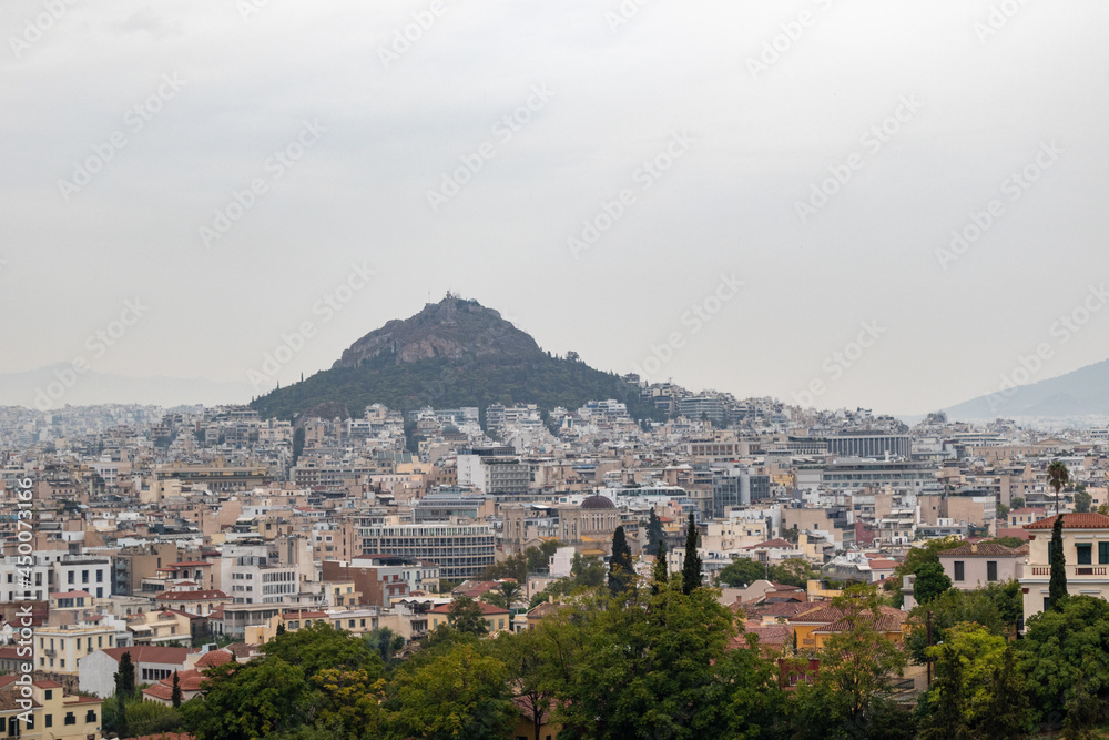 View on mount Lycabettus and Athens old city center with buildings architecture in gray foggy day from Areopagus - Hill near Acropolis