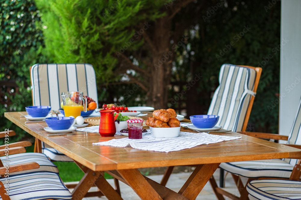 Obraz premium Laid table with food.Breakfast on the terrace.A table with food for a large family.A party.Banquet.Dinner on the summer terrace.Birthday on the street.Dining table with food.Lots of food on the table