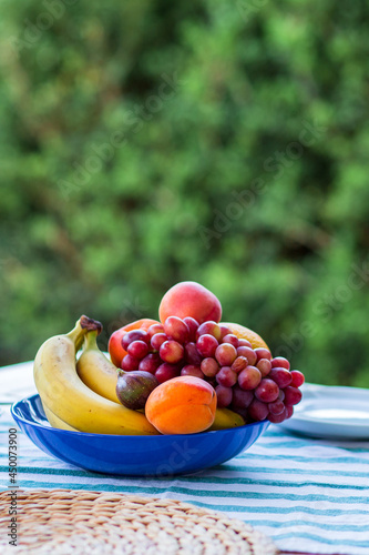 Fototapeta Naklejka Na Ścianę i Meble -  Fruit plate on the table.Fruit in a bowl.Banana, grapes, apricot, fig, peach.A plate with fruits on the table in summer.Summer.Vegetarian food.Food for vegans. diet. Healthy food.Healthy carbohydrates