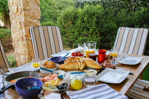 Breakfast at the table. Freshly baked bread on the table.Breakfast on the terrace for a large family.Freshly baked bread on the table.Nice pastries for breakfast.Bread and butter.Family eating sandwic photo