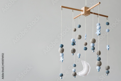 Baby crib mobile with stars, planets and moon. Kids handmade toys above the newborn crib. First baby eco-friendly toys made from felt and wood. Space for text. photo