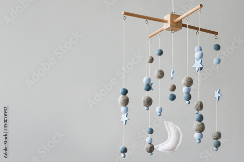 Baby crib mobile with stars, planets and moon. Kids handmade toys above the newborn crib. First baby eco-friendly toys made from felt and wood. Space for text.