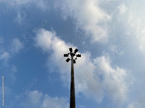 A street lamp that illuminates a street in one of the cities in Jakarta as seen from below against a background of blue sky and clouds