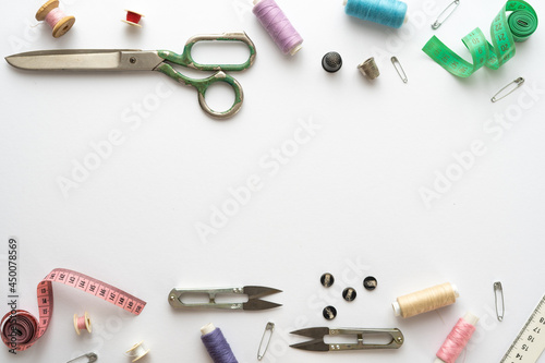 Flat lay composition with scissors and other sewing accessories on white background. Space for text