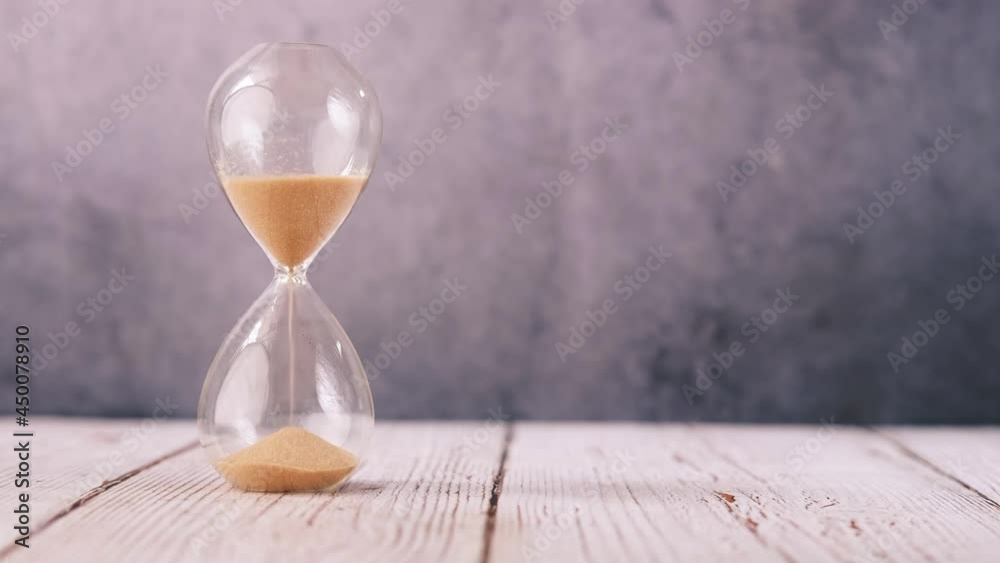 hourglass on table, sand flowing through the bulb of sandglass