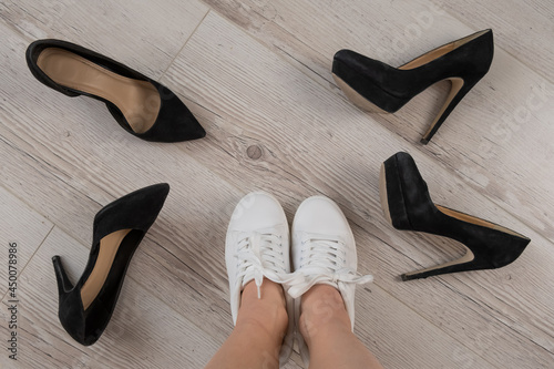 A woman chooses sports shoes instead of high-heeled shoes. Sneakers or shoes