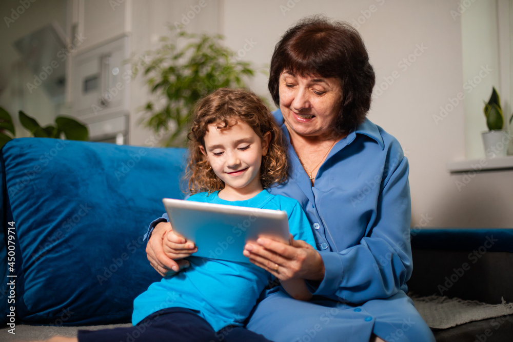 Grandmother with her granddaughter enthusiastically looking at the tablet screen