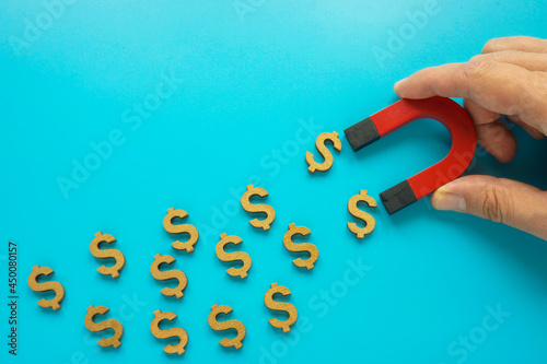 Canvas-taulu Money attracting concept. Hand holds magnet and dollar symbols.