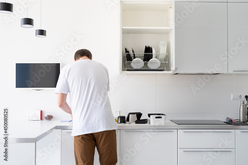 Man in white t shirt washing dishes in the kitchen