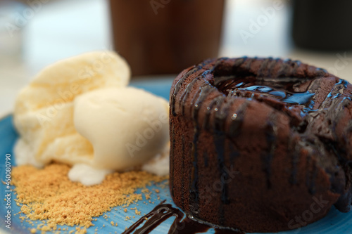 Summer cafe concept: vanilla ice cream with hot chocolate souffle or lava cake served on blue cake, light color wooden table photo