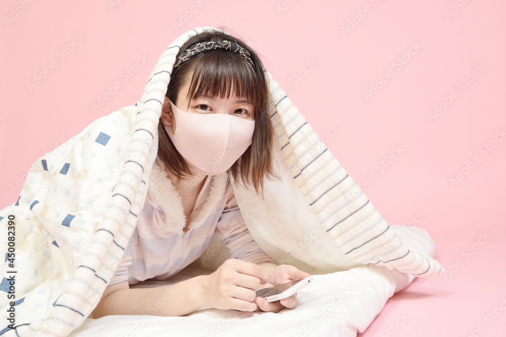 マスクを着けてスマホを操作する若い女性 マスクを着けてスマホを操作する若い女性