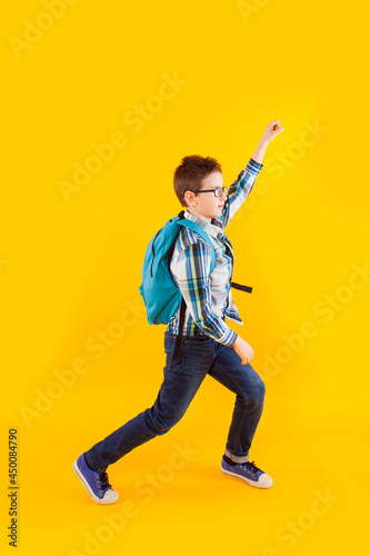 Jumping emotional schoolboy on the yellow background