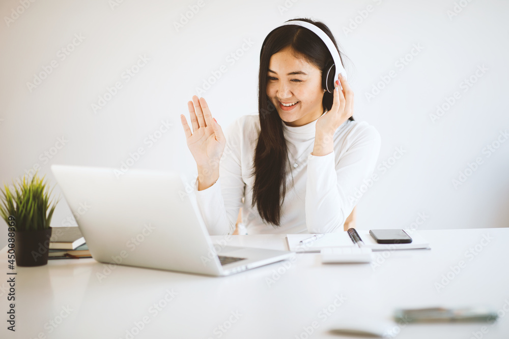 Asian young female student sitting at the laptop computer, using headphones when studying. Asian young female student sitting at the laptop computer, using headphones when studying.