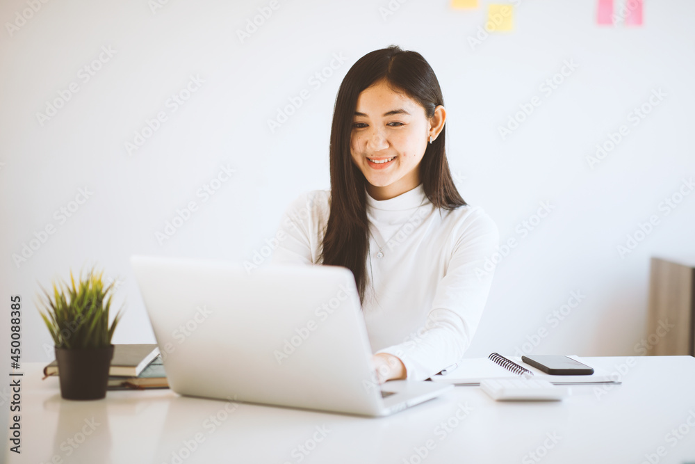 Asian young female student sitting at the laptop computer, using headphones when studying. Asian young female student sitting at the laptop computer, using headphones when studying.
