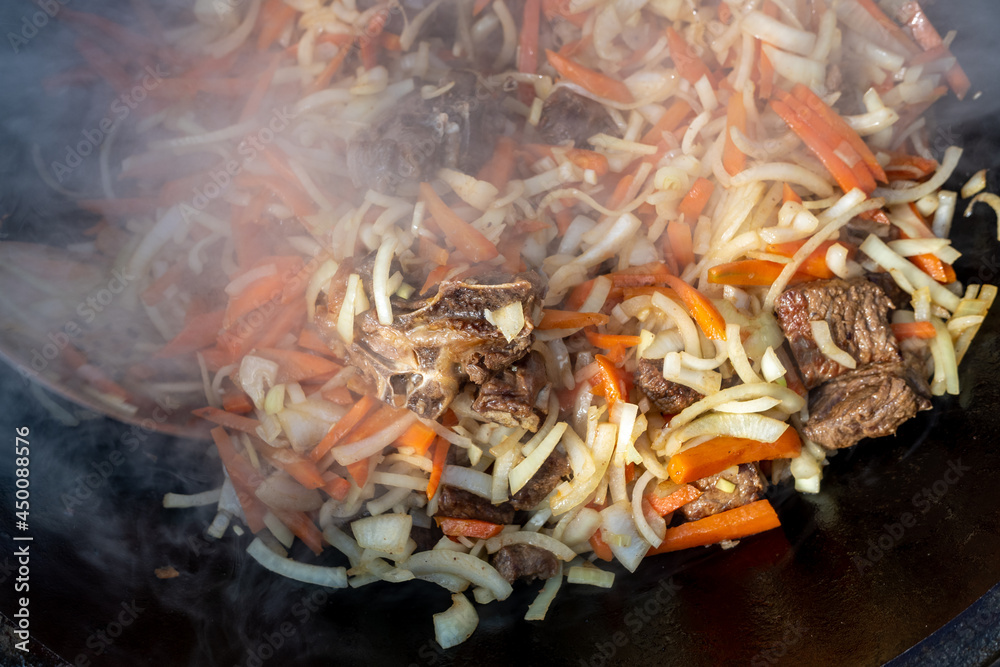 Fry meat, carrots, onions, rice in a large cast-iron cauldron, cook pilaf.