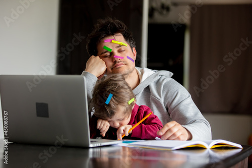 young father works at a computer at home with a child