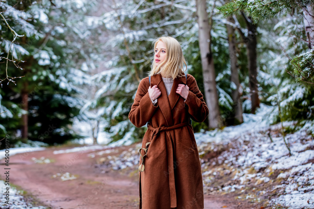 Style blonde woman in coat in snow forest