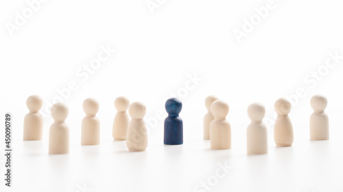 A wooden figure standing with a team to influence and empower. Concept of leadership, successful competition winner and Leader with influence and Social distancing for a new normal lifestyle