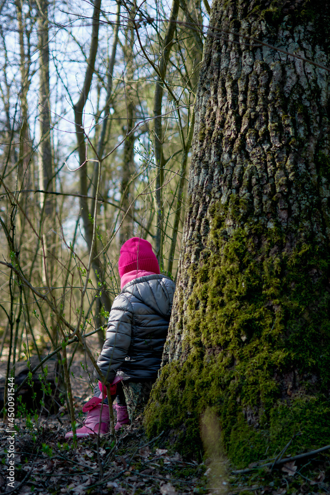 Little girl having fun in beautiful forest with dry yellow leaves and green moss