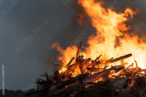 Midsummer traditional bonfire on tiny island Abruka in Baltic Sea. Festive eve of the Summer Solstice. Orange flames over high heap of firewood.