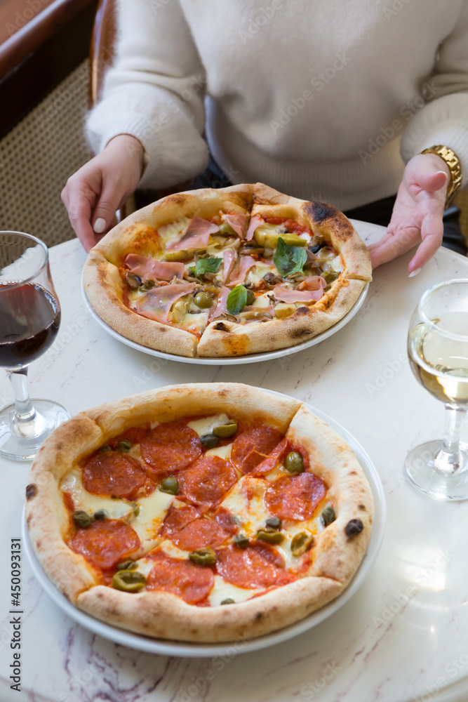 Two women eating pizzas and drinking wine