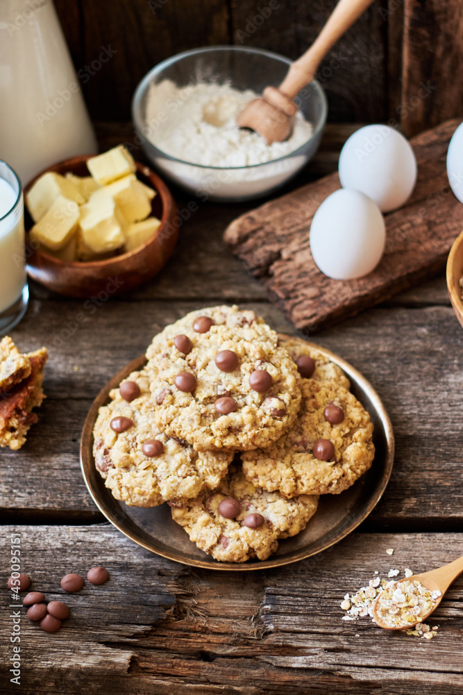 Oatmeal Chocolate Chip Cookies. Wooden background, side view, eggs, oatmeal, flour, chocolate chips, ingredients, milk, butter, rustic.