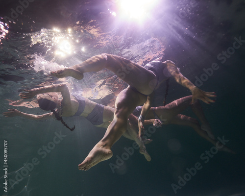 young girls swim underwater in the pool