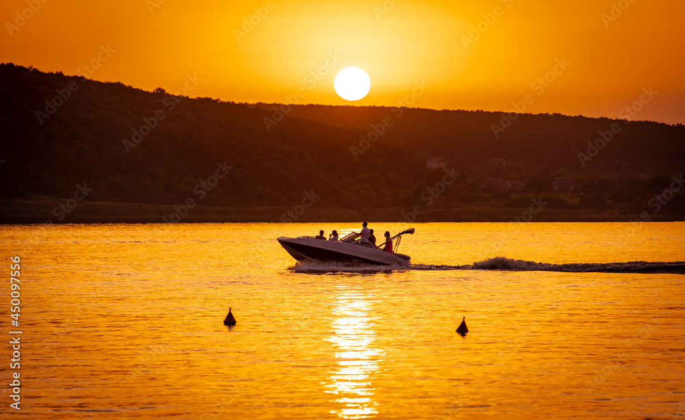Silhouette of motorboat on the river at summer sunset