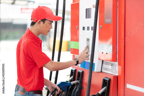 male worker holding petrol hose and choosing gasoline at the gas station