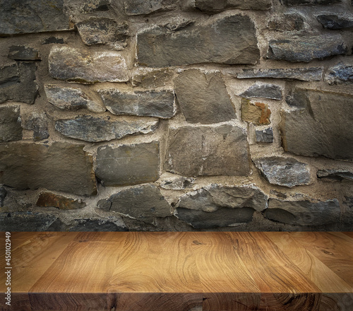Fotografie Wooden table top with stonewall background texture