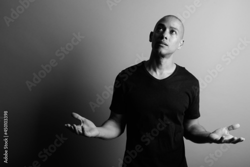 Handsome bald man wearing black shirt against gray background