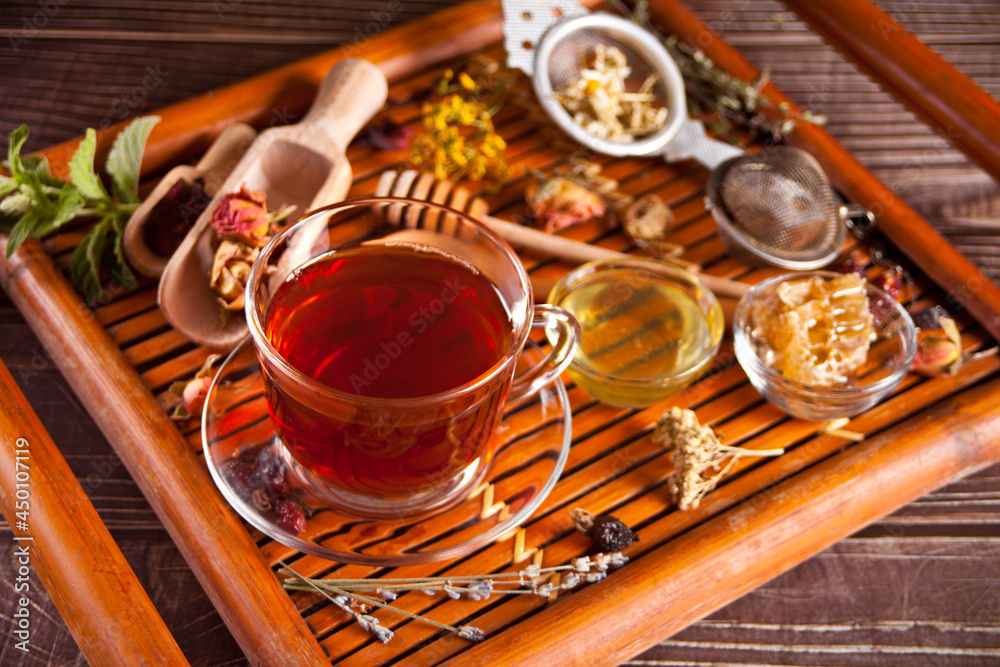 Fototapeta premium Cup of herbal tea with flowers and various dried herbs on the tray.