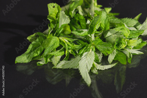 Mint leaves on black background. Peppermint lying on table