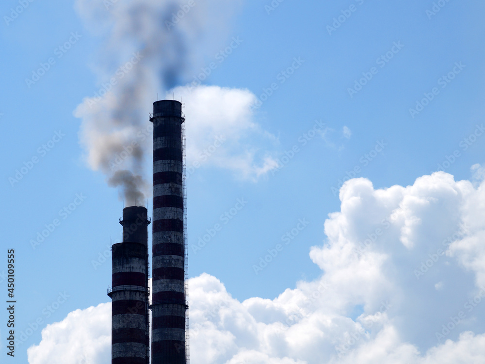 smoking chimneys against the background of a clear sky and white clouds