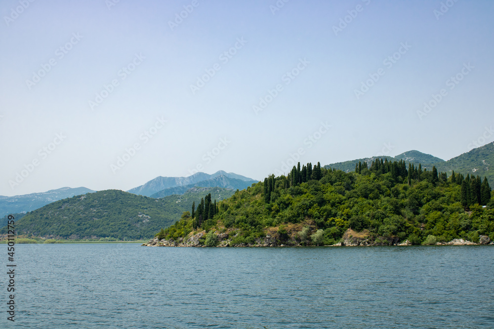 Landscape with lake and green mountains against the background of a clear sky. Panoramic beautiful view on largest lake. Wonderful summer day. Landscape with lake and green mountains against the background of a clear sky. Panoramic beautiful view on largest lake. Wonderful summer day.