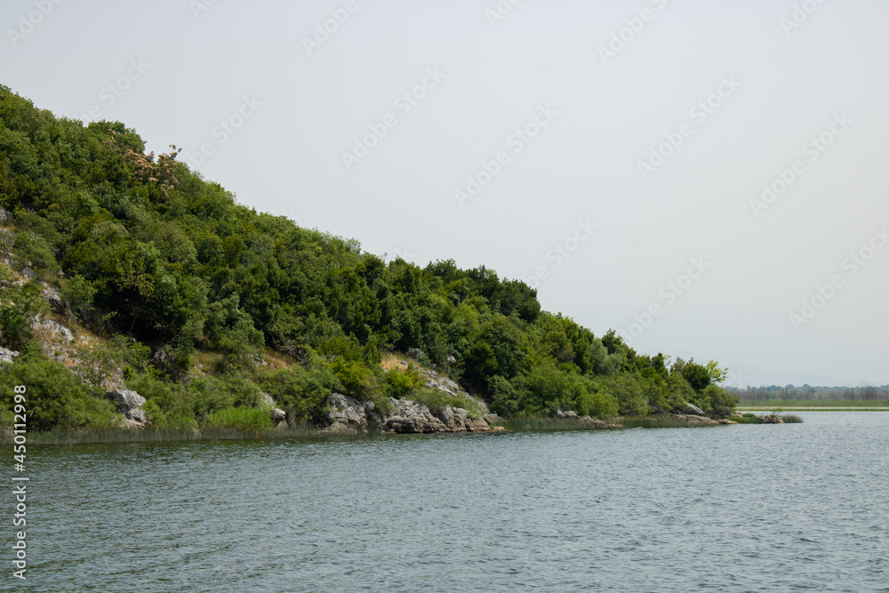 Croup of green mountains around beautiful lake. Landscape on the natural park highlands. Panoramic view on the lake shore.