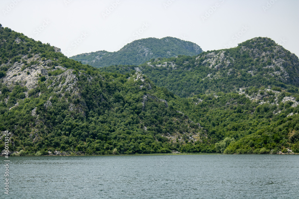 Croup of green mountains around beautiful lake. Landscape on the natural park highlands. Panoramic view on the lake shore.